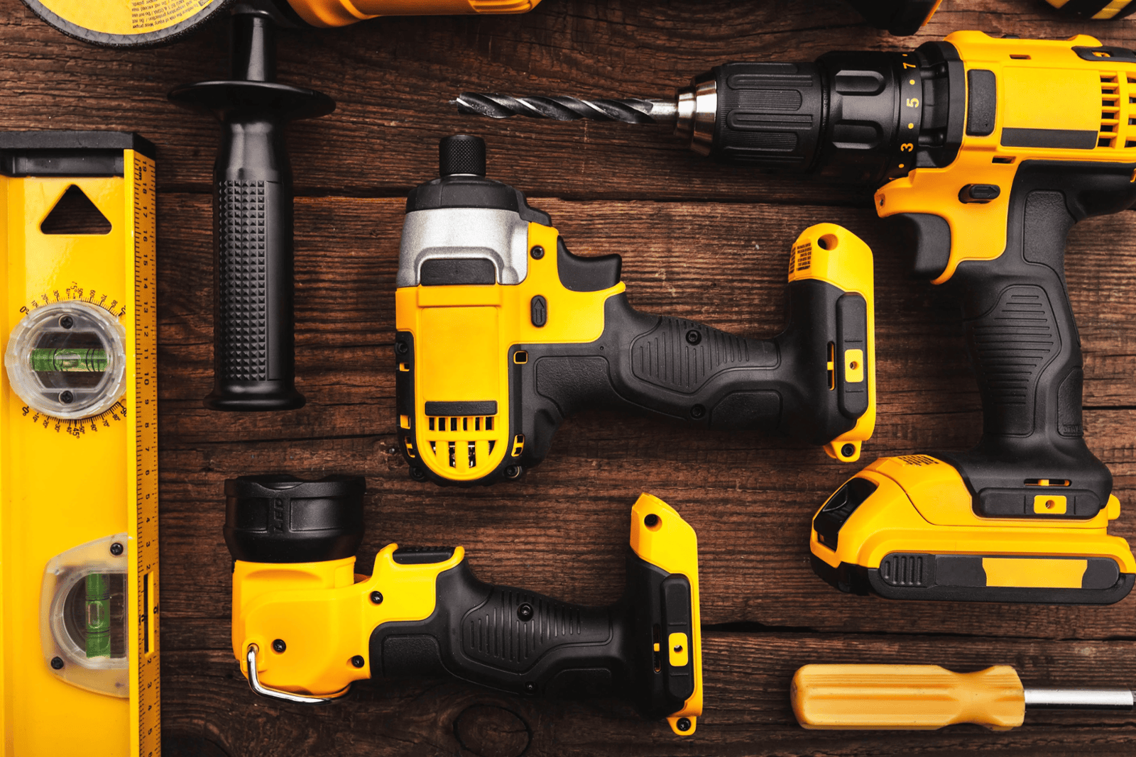 A collection of power tools including a cordless drill, angle grinder, electric saw, and sander arranged neatly on a wooden workbench, ready for use in DIY and construction tasks.